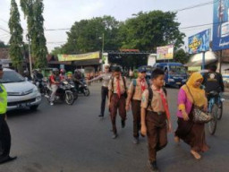AKP Mellsya Kasat Lantas Pasuruan Sebrangkan Pelajar Saat Pulang Sekolah.